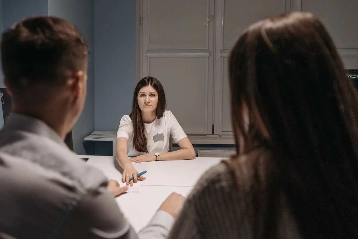 A couple talking to a clinician across a consulting room table